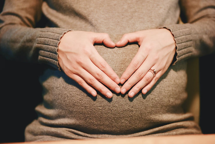 Pregnant woman lovingly placing her hands on her abdomen, symbolizing the joy and connection of motherhood.