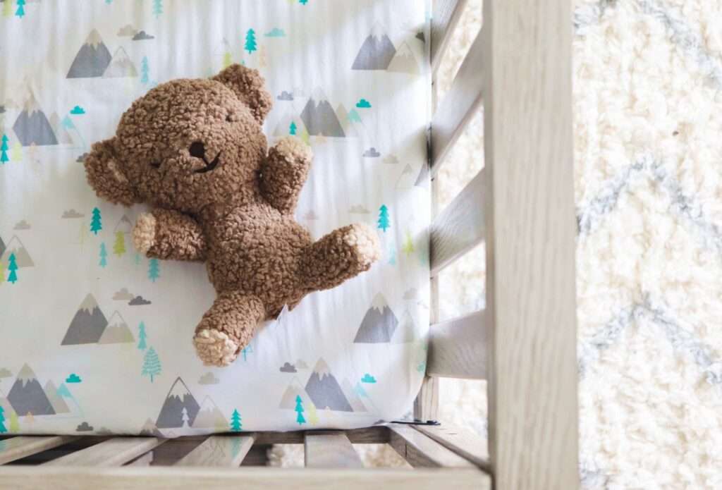 teddy bear stuffed animal in a baby crib