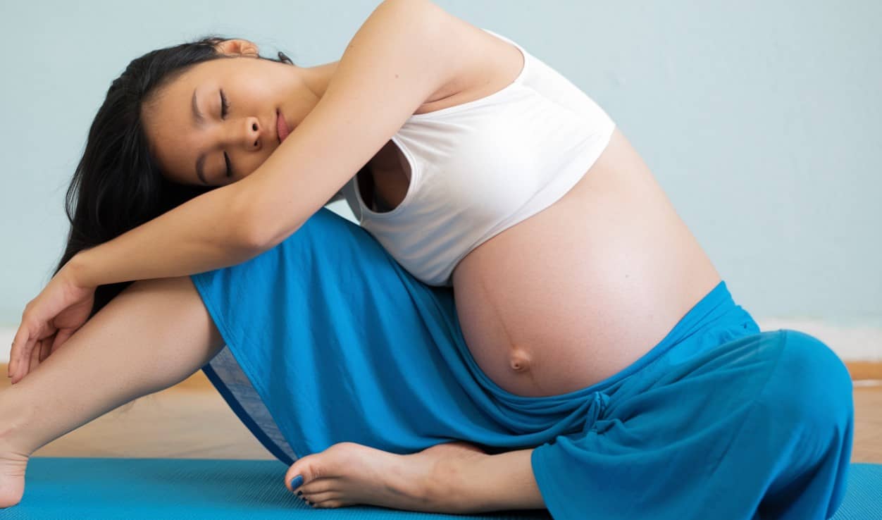 Pregnant woman practicing prenatal yoga in a serene setting